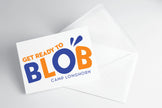 A folded note card with 'Get Ready to Blob - Camp Longhorn' text and a blue and orange design, placed on a white background.
