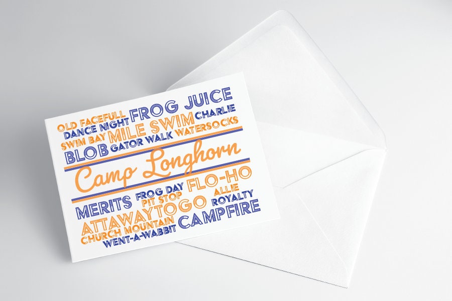 A folded note card with a 'Camp Longhorn' design, featuring text in blue and orange on a white background, placed on a clear background.