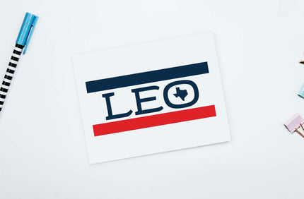 A personalized note card with the name 'Leo' written in a stylized font, accompanied by a small drawing of a lion, placed on a table with a pen and highlighter.