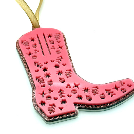 Pink cowboy boot-shaped ornament with decorative patterns on a white background