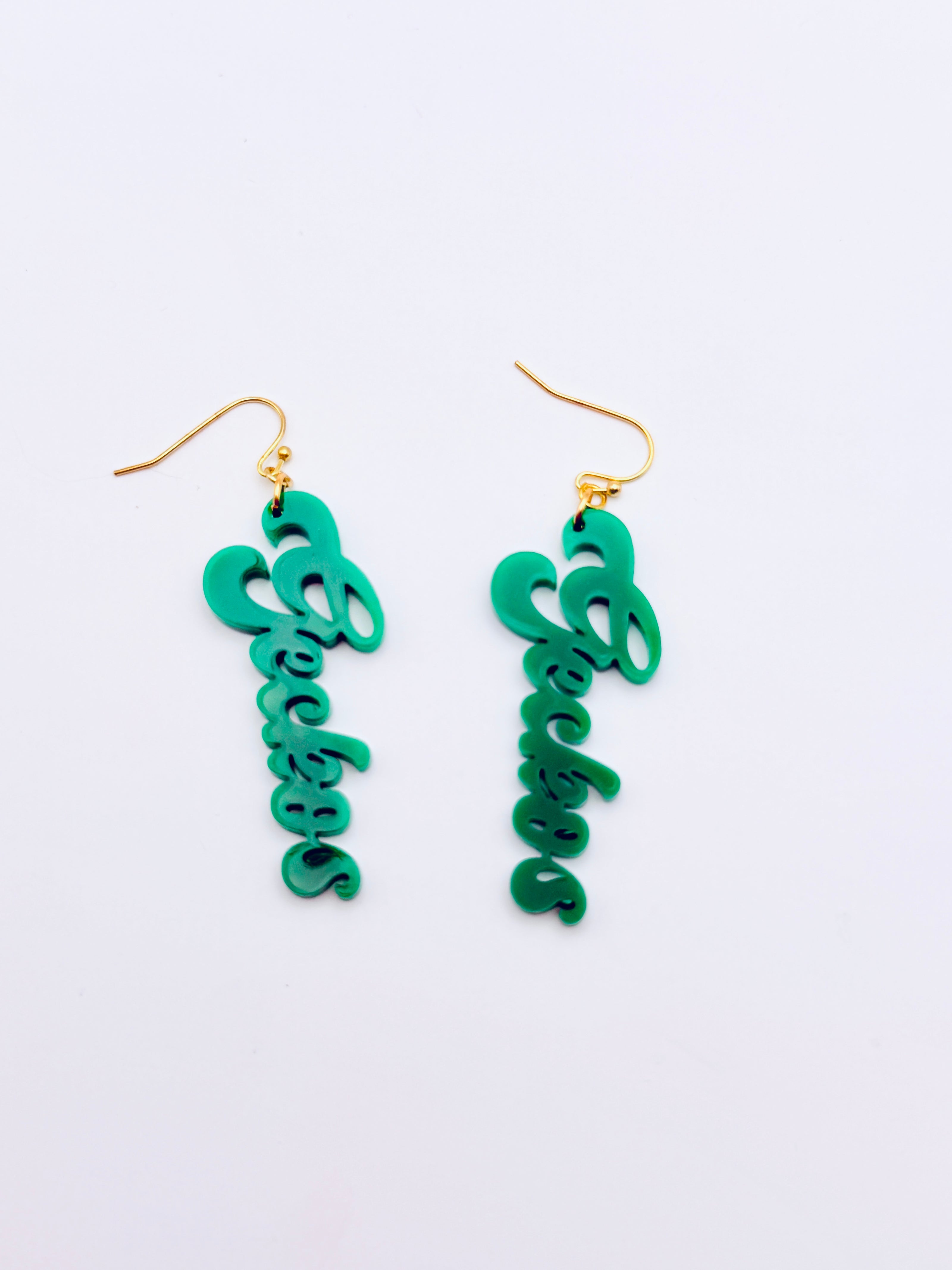 Green script earrings on a light blue background