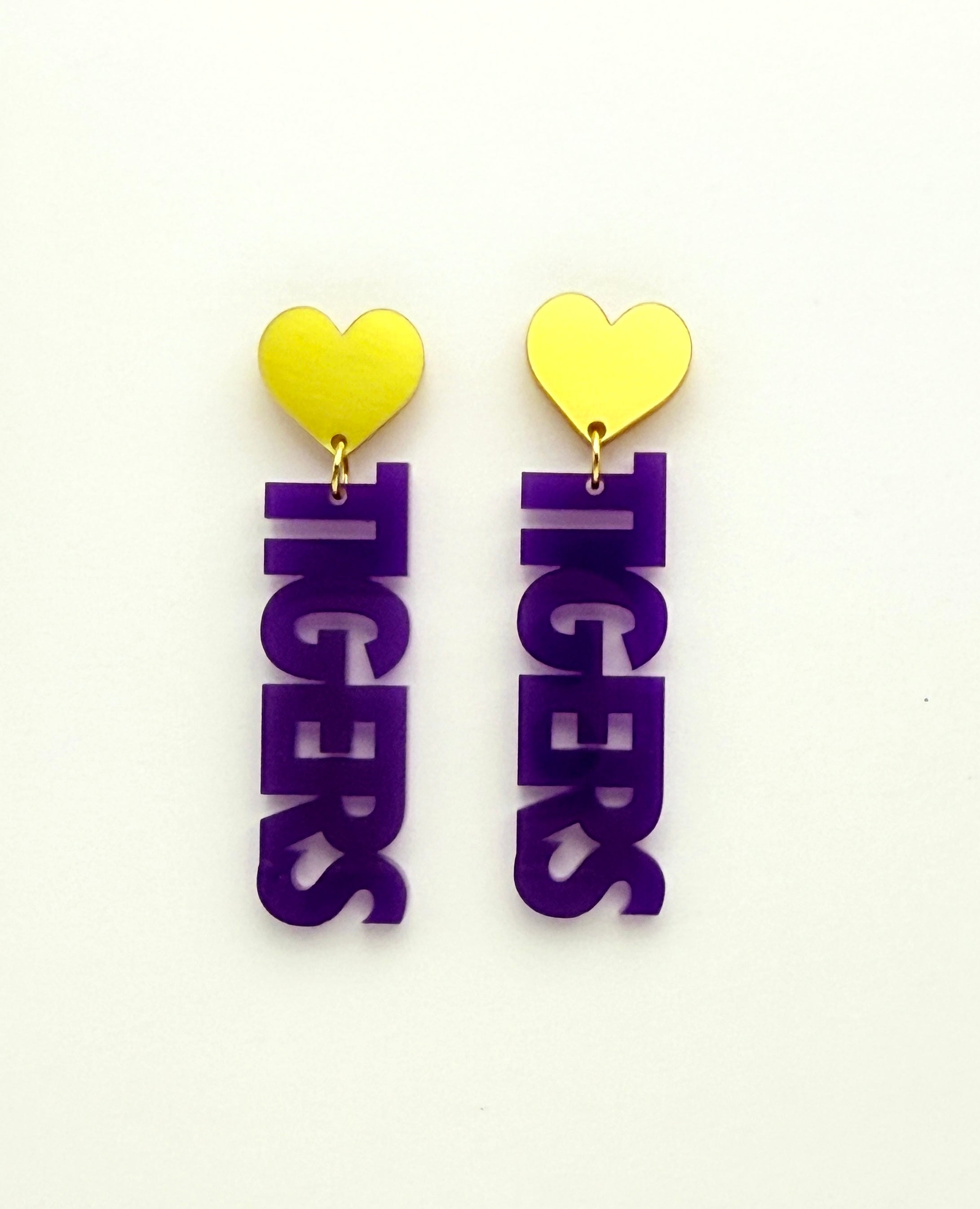 Pair of earrings with yellow heart tops and purple 'TIGERS' letters on a white background