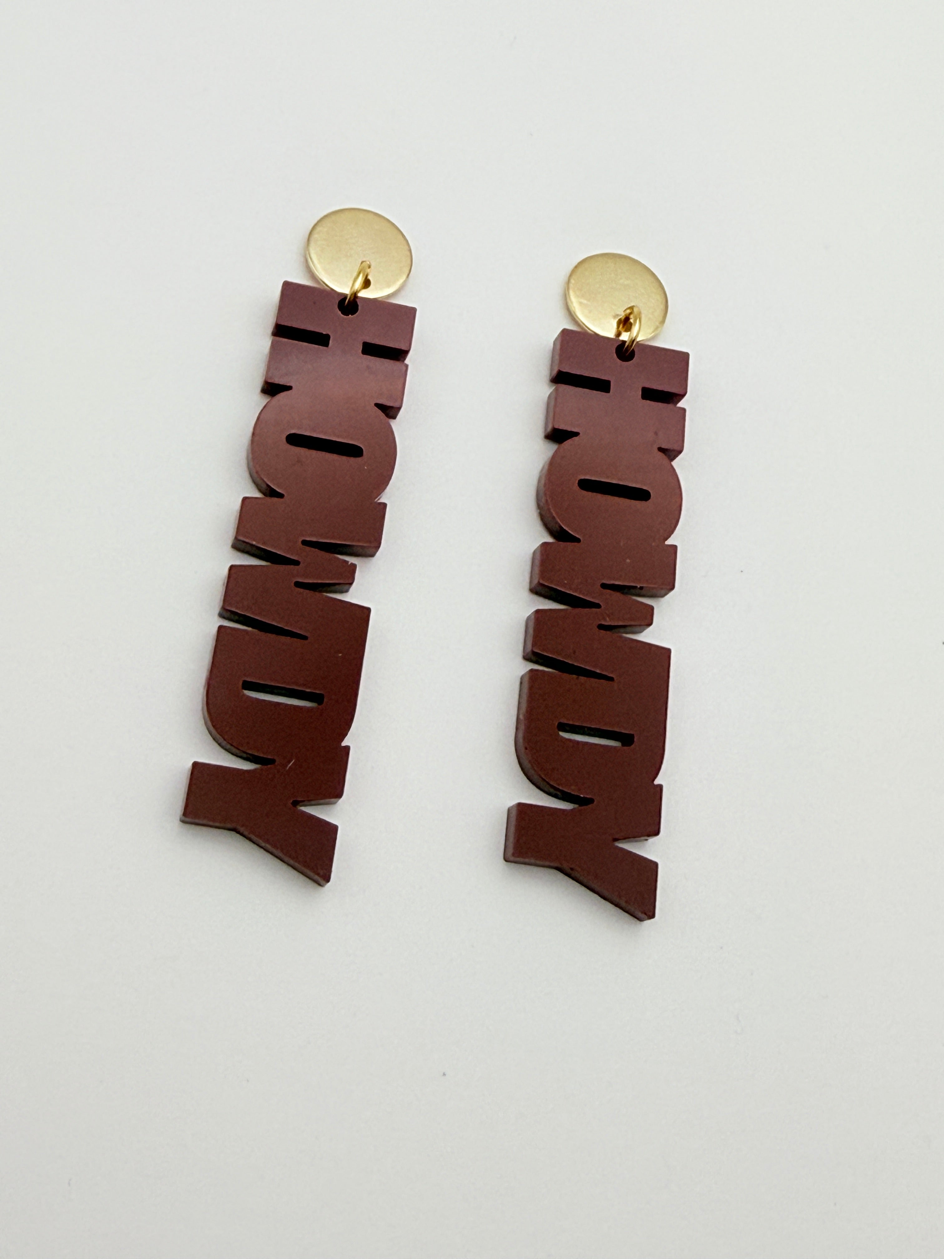 Pair of 'HOWDY' earrings on a light gray background