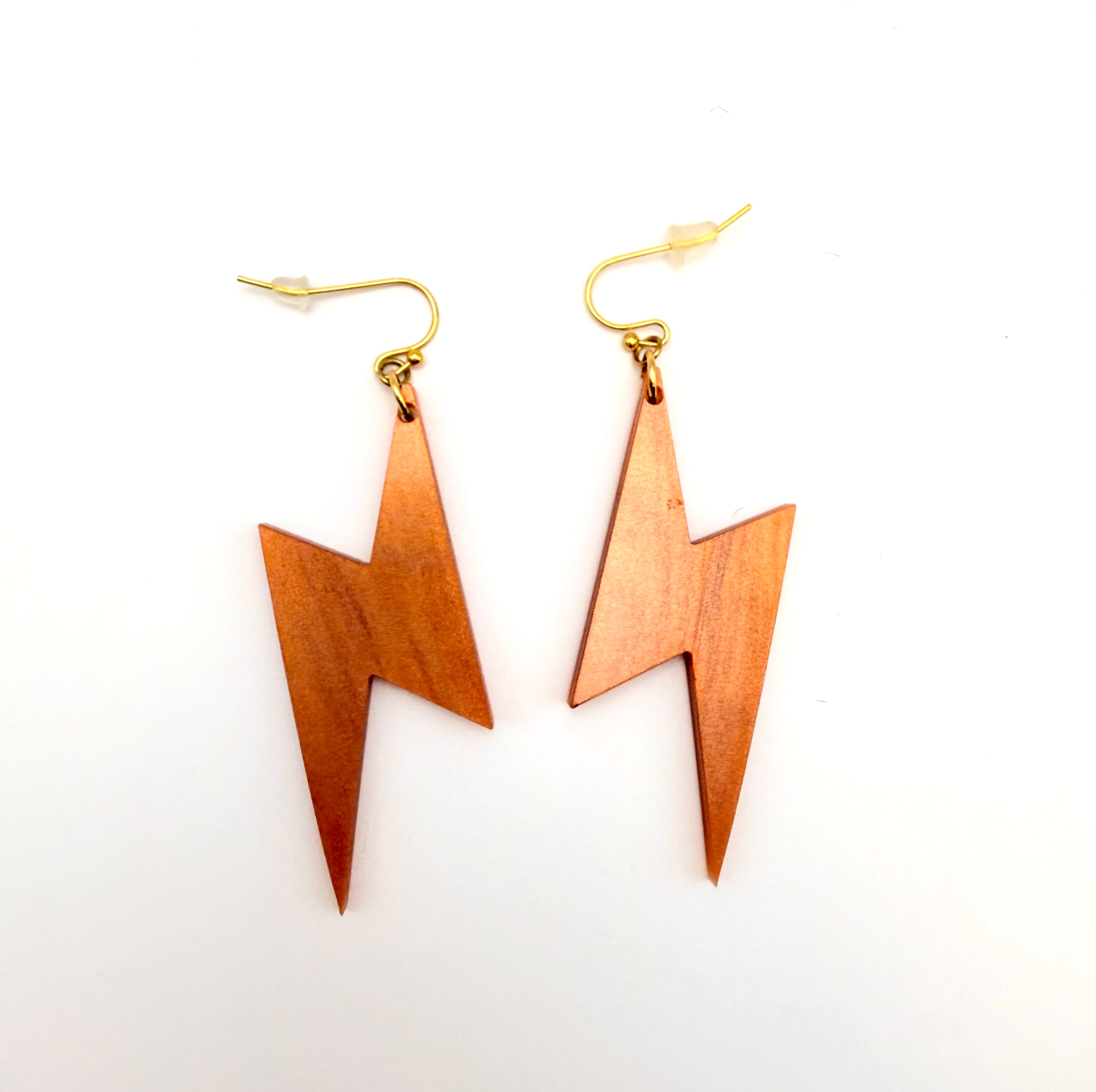 A pair of lightning bolt drop earrings made of copper-colored acrylic with gold-tone fishhook wires, displayed on a clean white background.
