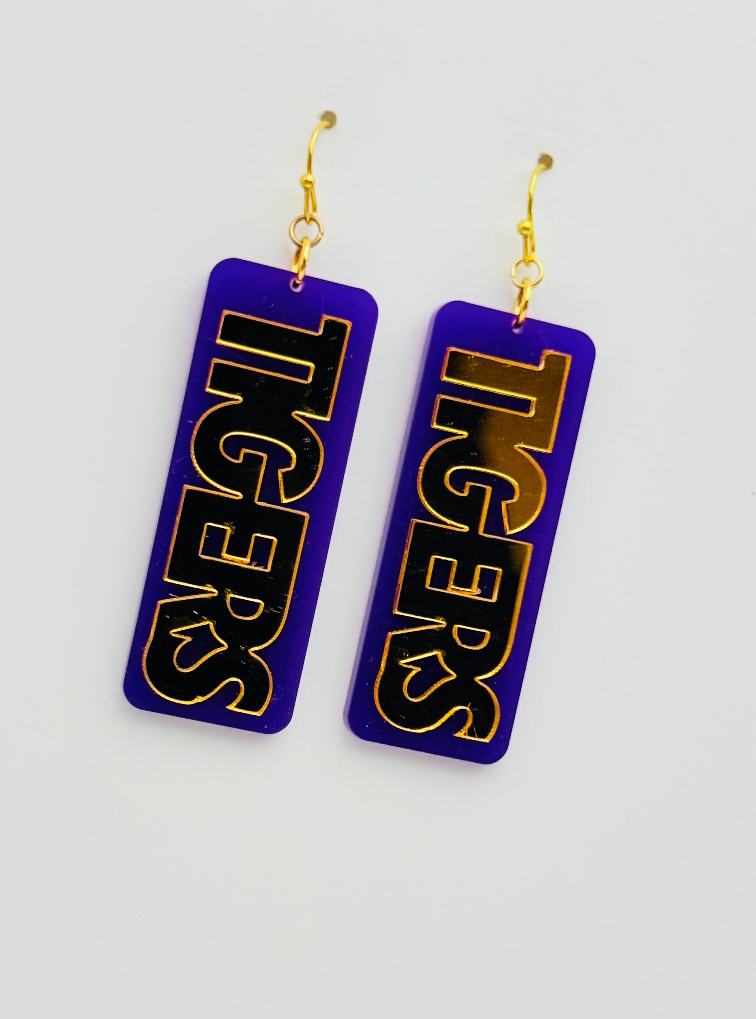 Pair of earrings with 'TIGERS' text on a purple background
