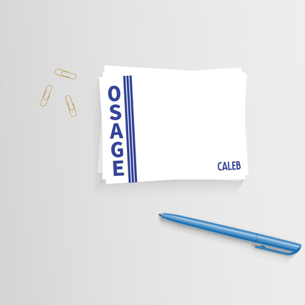 A white notecard with 'OSAGE' printed in blue uppercase letters and the name 'Caleb' in blue script. Accompanied by a blue pen and envelopes with a camper's notes layout in the background.