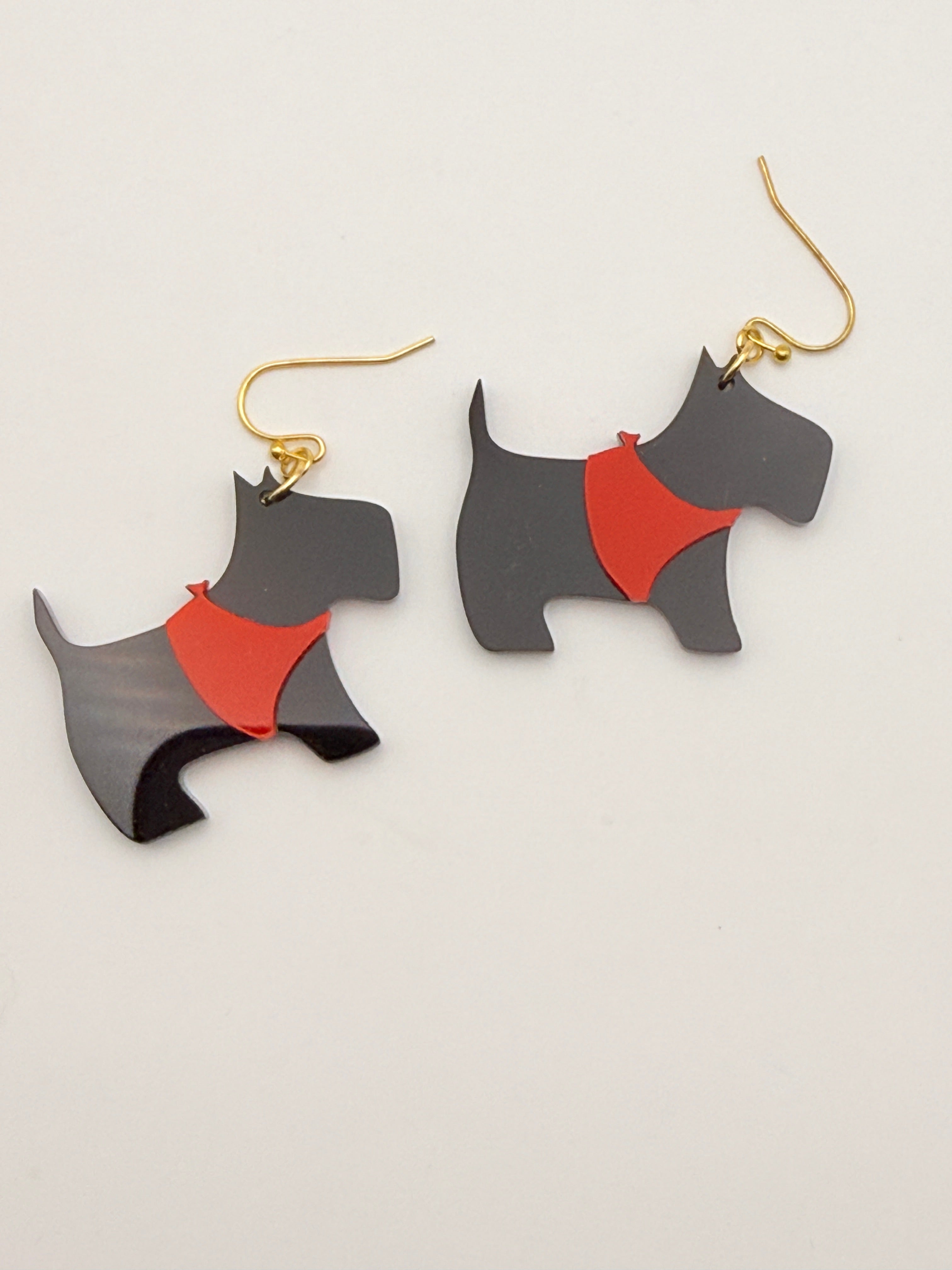 Black and red dog-shaped earrings on a light gray background