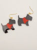 Black and red dog-shaped earrings on a light gray background