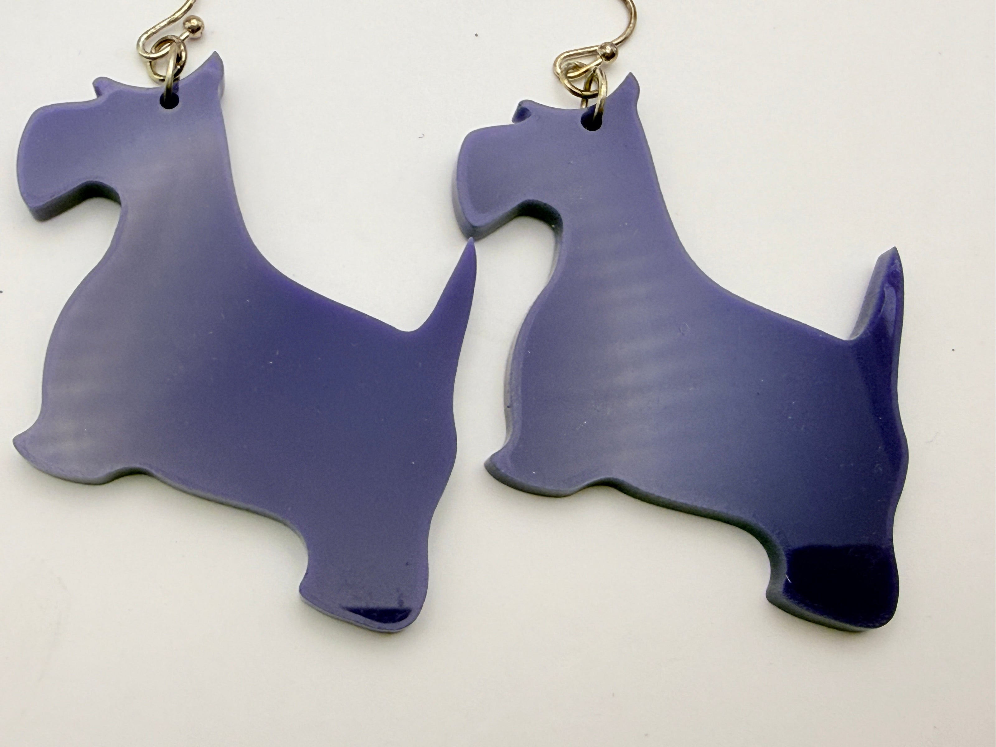 Purple dog-shaped earrings on a white background