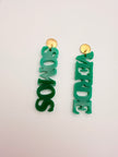 Green earrings with 'VERDE SOMOS' text on a light gray background