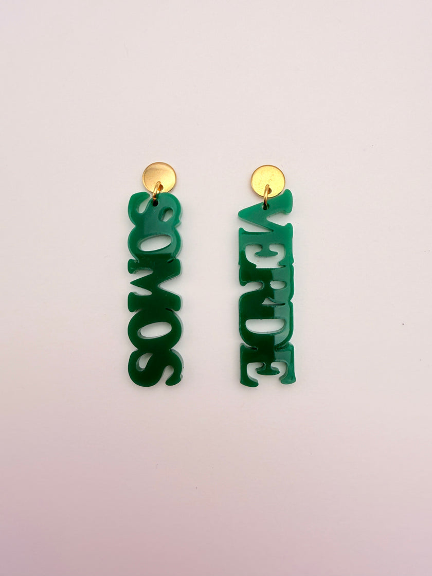 Green earrings with 'VERDE SOMOS' text on a light pink background