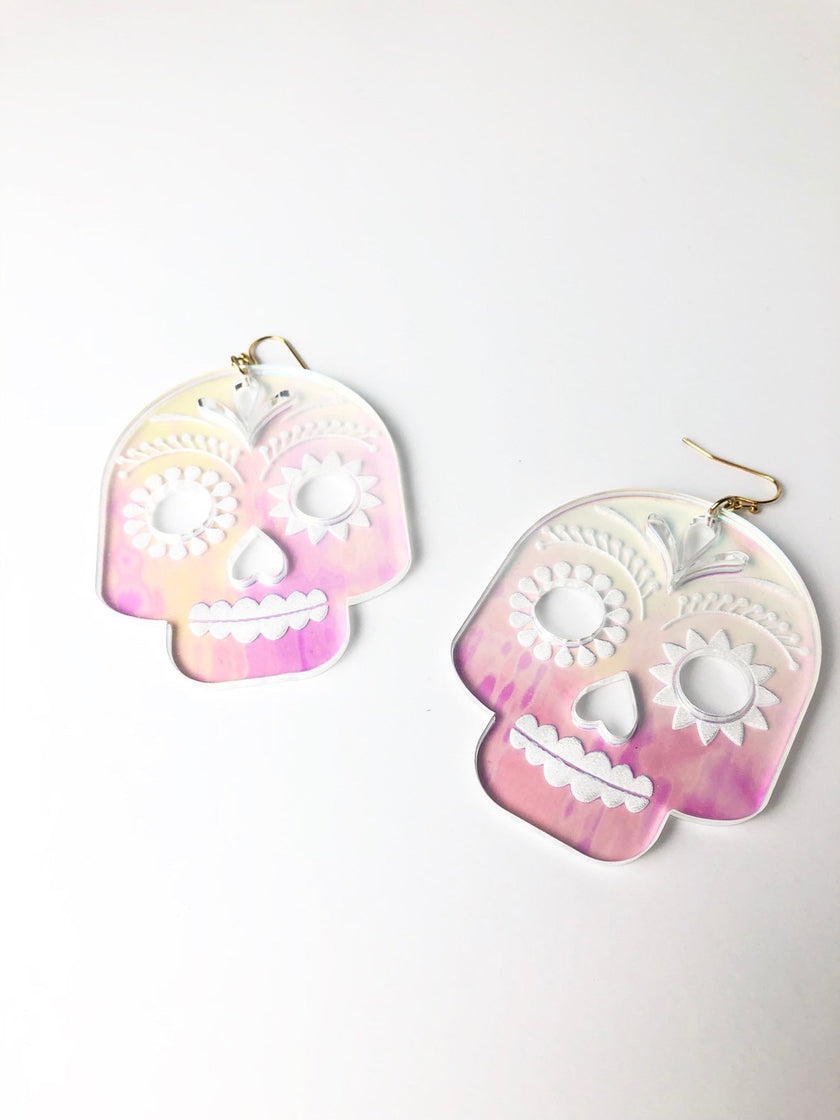 Pair of skull-shaped earrings with pink and white gradient on a white background
