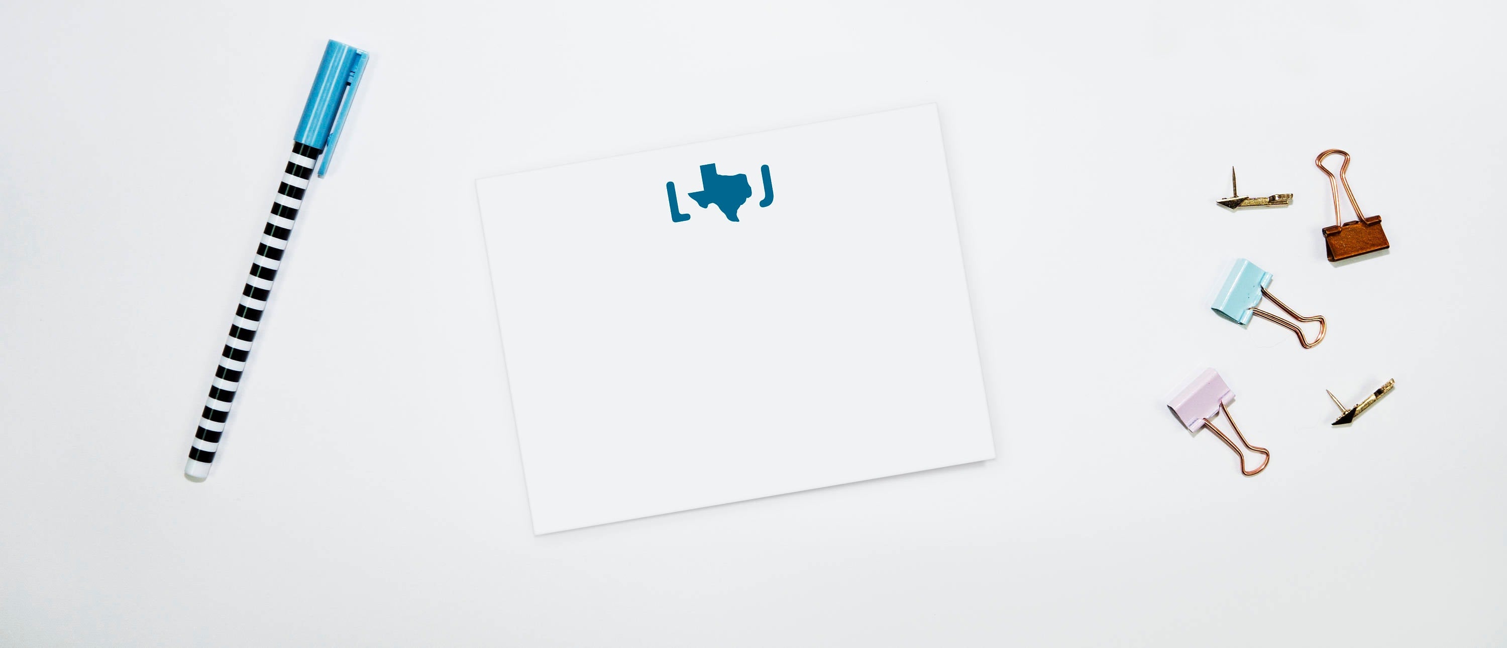 A set of personalized note cards with a Texas monogram design, along with envelopes and a pen, displayed on a white background.