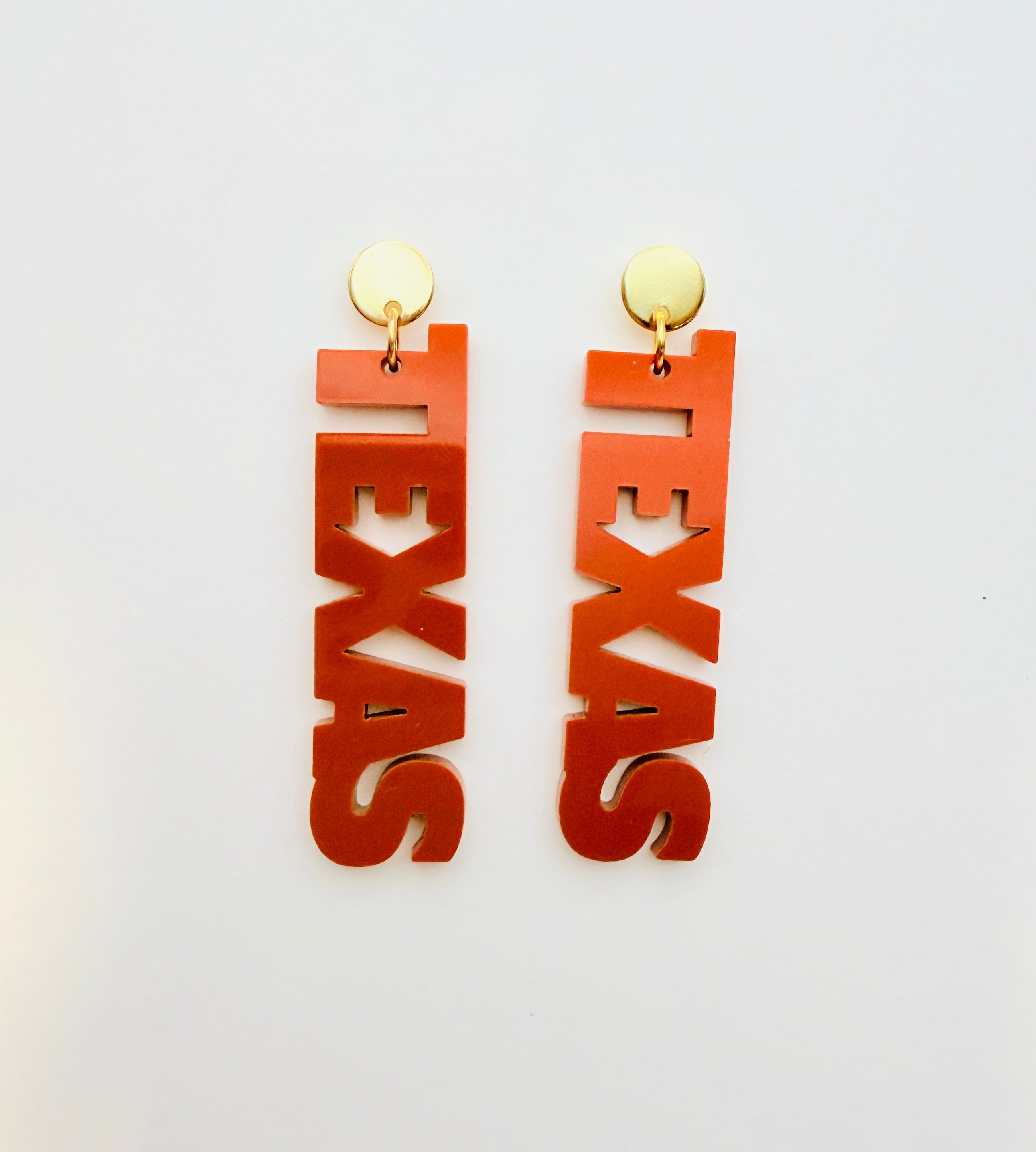 Orange 'TEXAS' earrings on a white background