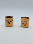 Two tan cylindrical bandana slides with engraved black designs, one featuring a longhorn skull and the other the outline of Texas, on a light gray background.