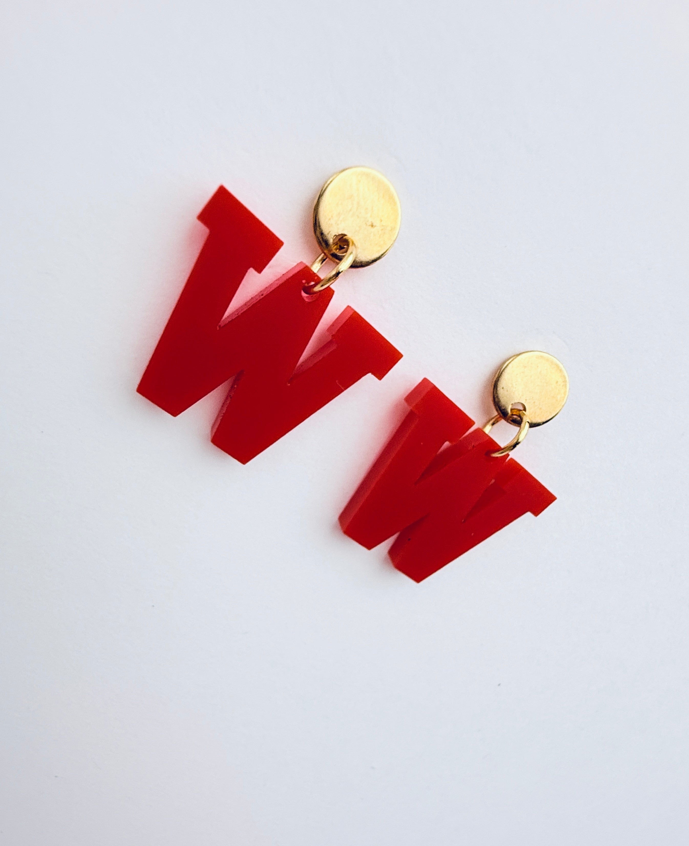 Red letter 'W' earrings with gold studs on a white background