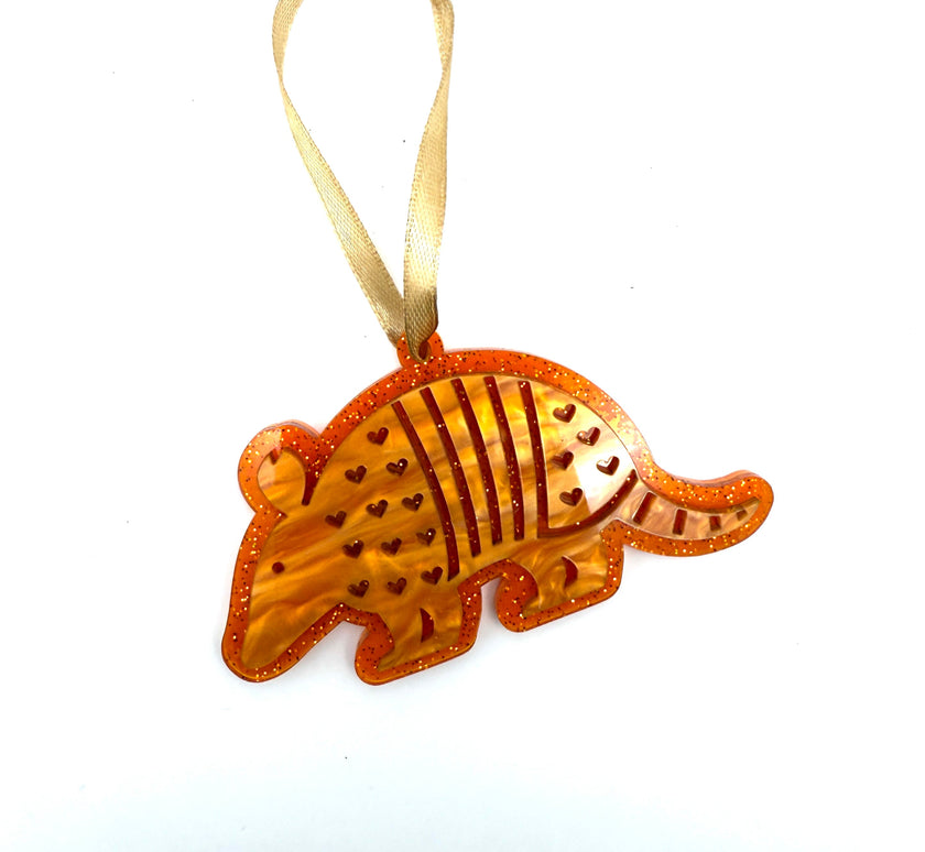 Orange armadillo ornament with a gold ribbon on a white background