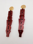 Pair of maroon 'howdy' earrings with gold ends on a white background
