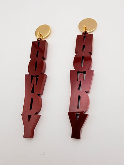 Pair of maroon 'howdy' earrings with gold ends on a white background